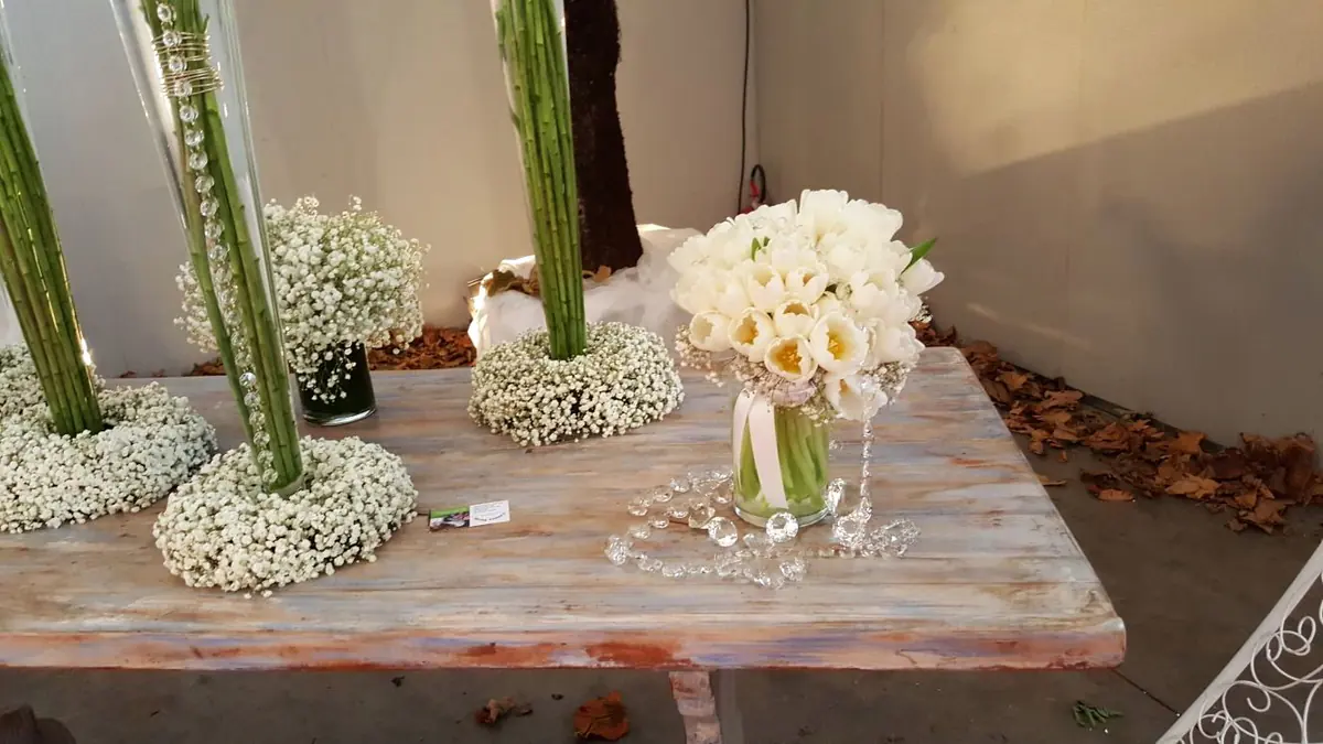 Tavolo espositivo con gypsophila, rose bianche e vetri