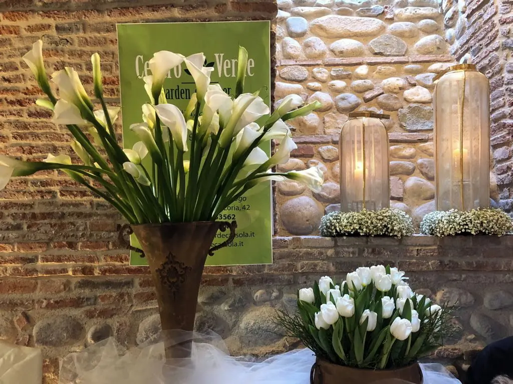 Calle e tulipani bianchi in anfora, su fondo di sassi a vista