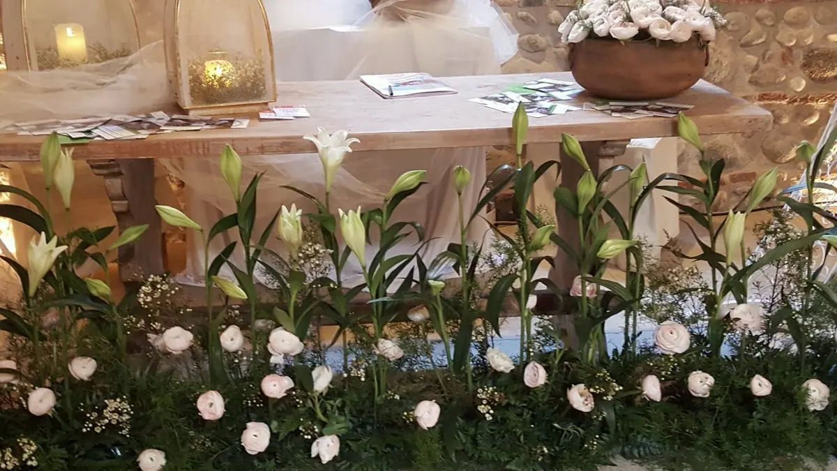 Tavolo lungo fiorito con rose bianche e lilium per un evento