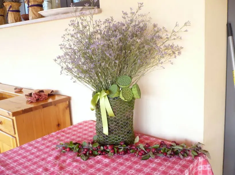 Composizione alta con verde e bacche in vaso intrecciato