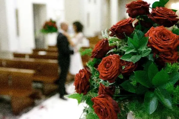 Primo piano di una composizione di rose rosse in chiesa