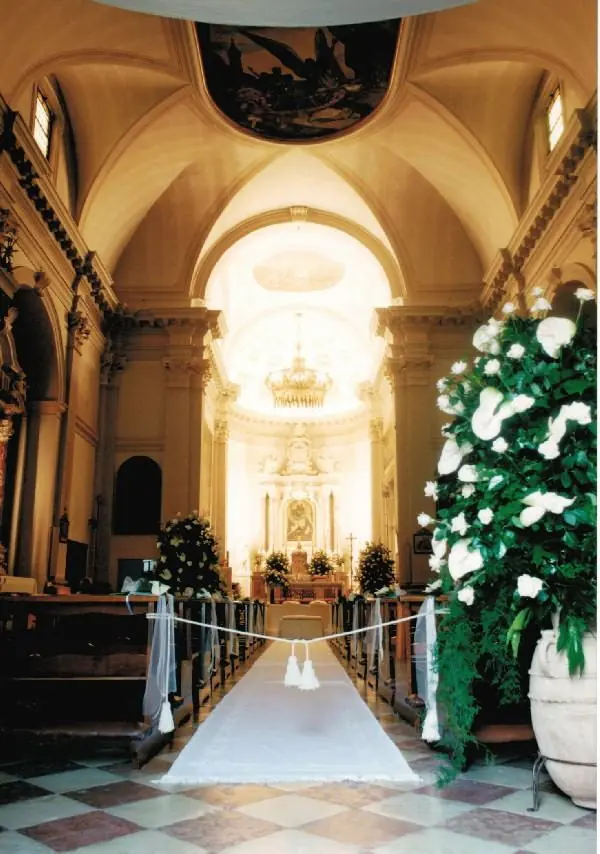 Navata addobbata con verde e fiori bianchi verso l'abside