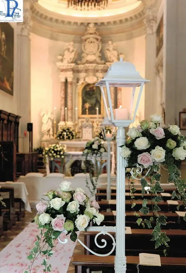 Lampioni bianchi e composizioni rosa cipria lungo il tappeto