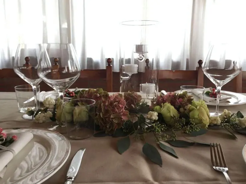 Tavolo del ricevimento con centrotavola basso di fiori e frutta