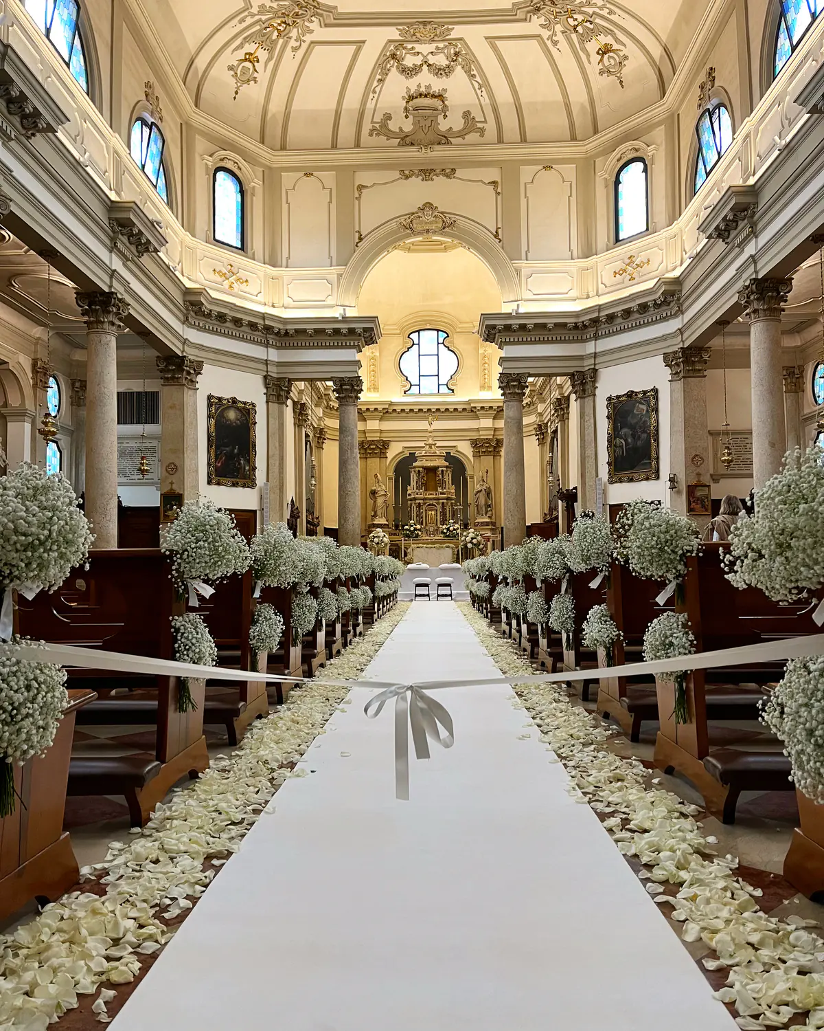 Navata di chiesa con passatoia bianca, petali e sfere di gipsofila